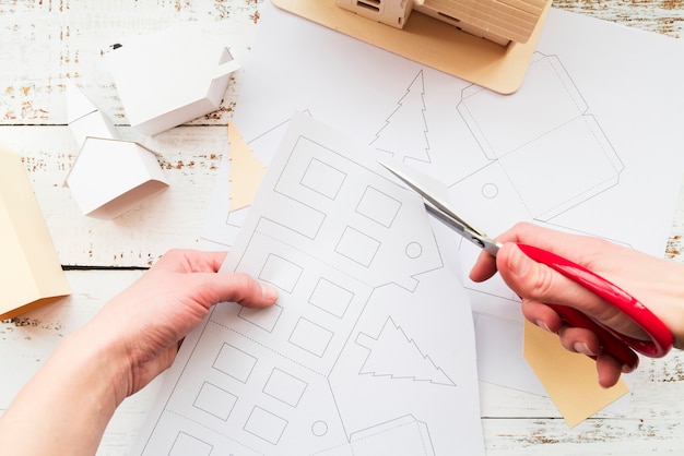 Close-up of a person cutting the house drawing with scissor