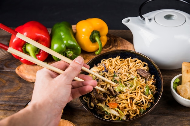 Close-up of a person eating the friend udon noodles with chopsticks