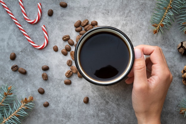 スタッコの背景を持つコーヒーカップを保持しているクローズアップの人