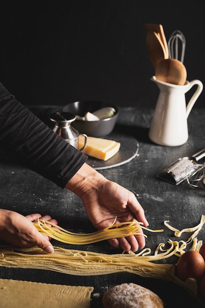 Free photo close-up person holding dough for spaghetti