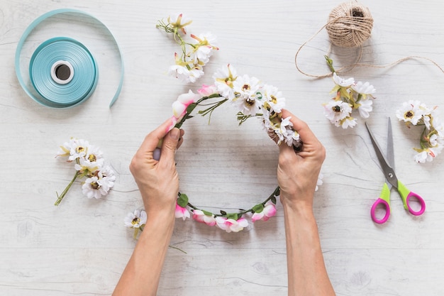 Close-up of a person holding fake floral wreath on textured backdrop