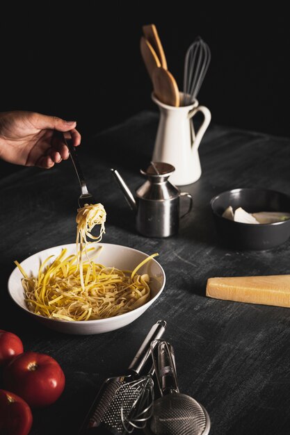 Close-up person holding fork with pasta 