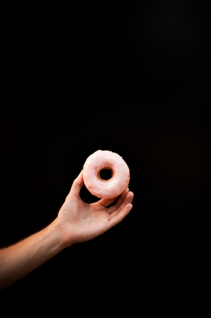 Крупный план лица, держащего глазированный пончик