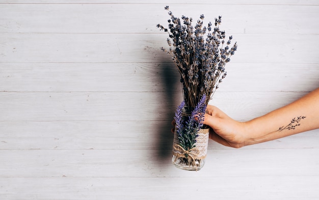 Close-up of a person holding lavender bouquet against wooden backdrop
