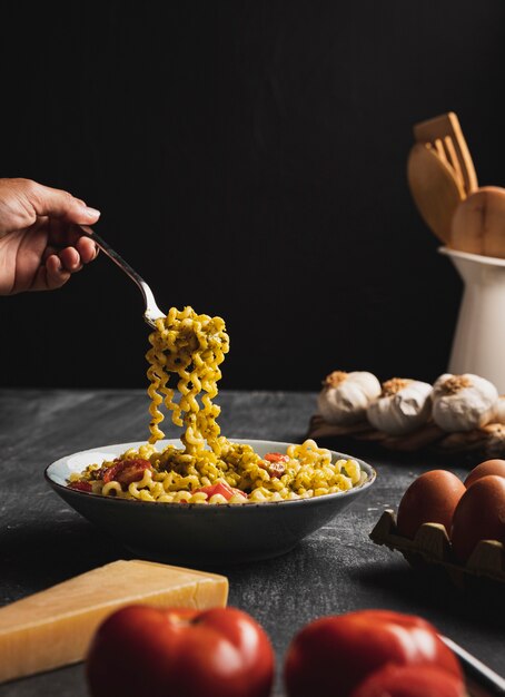 Close-up person holding pasta with fork