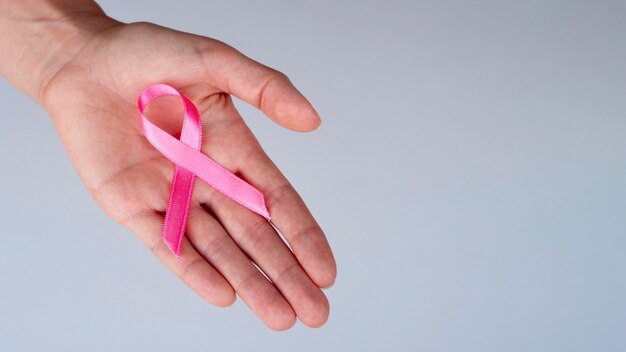 Close-up person holding pink ribbon