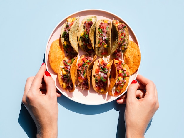 Close-up person holding plate with tacos