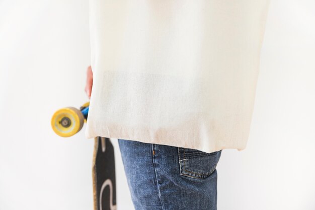 Close-up of a person holding skateboard against white backdrop