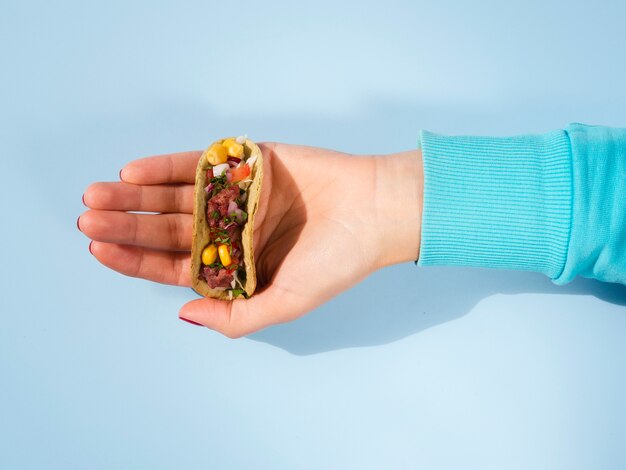 Close-up person holding small taco