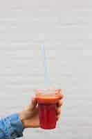 Free photo close-up of a person holding smoothie in plastic disposable cup with straw