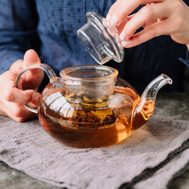 Close-up person holding the teapot lid