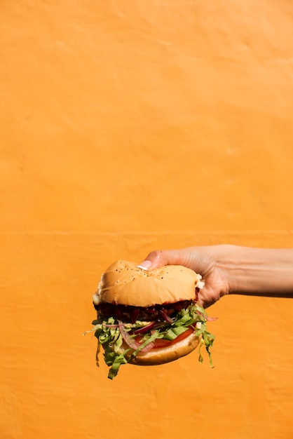 Free photo close-up person holding up delicious burger