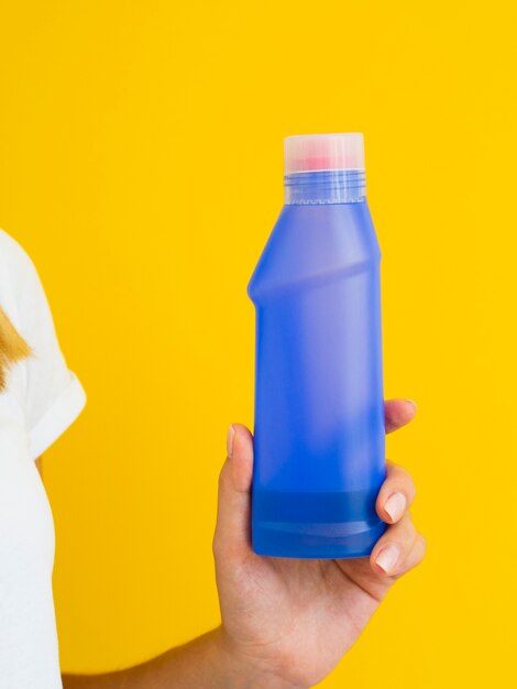 Close-up person holding up purple detergent bottle