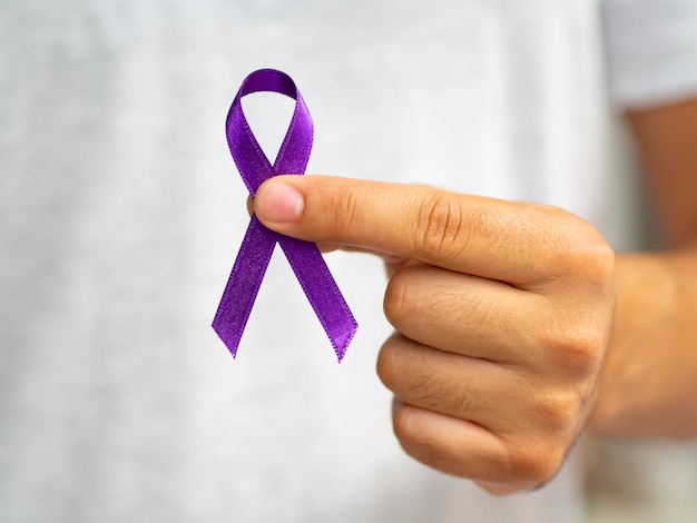 Close-up person holding up purple ribbon