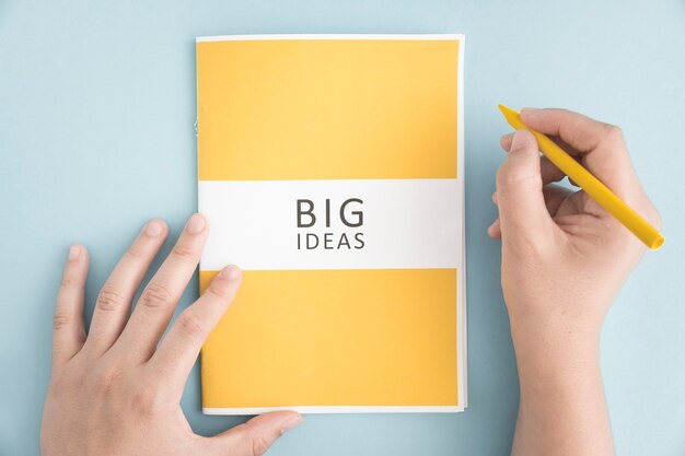 Крупным планом человек, холдинг желтый карандаш с большой идеей книга на синем фоне