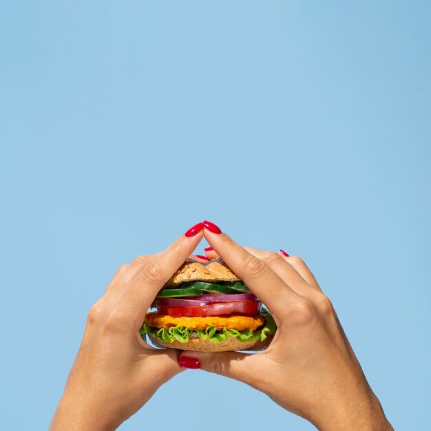 Close-up person holding a yummy veggie burger