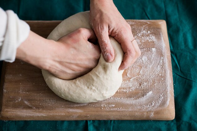 Close-up of a person kneading the dough on chopping board