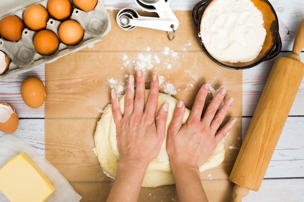 Close-up of a person kneading the dough with ingredients on wooden table