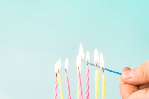 Close-up of a person lightning candles against blue background