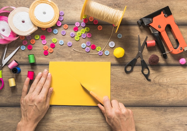 Close-up of a person making greeting card with spool; buttons and ribbons