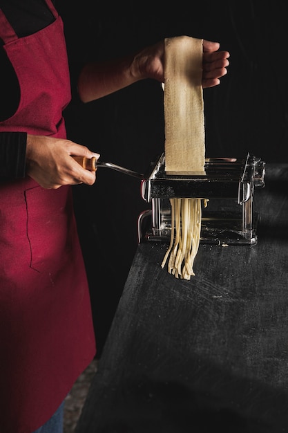 Close-up person making pasta with dark background