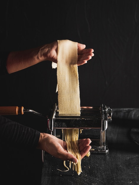 Free photo close-up person making pasta with machine