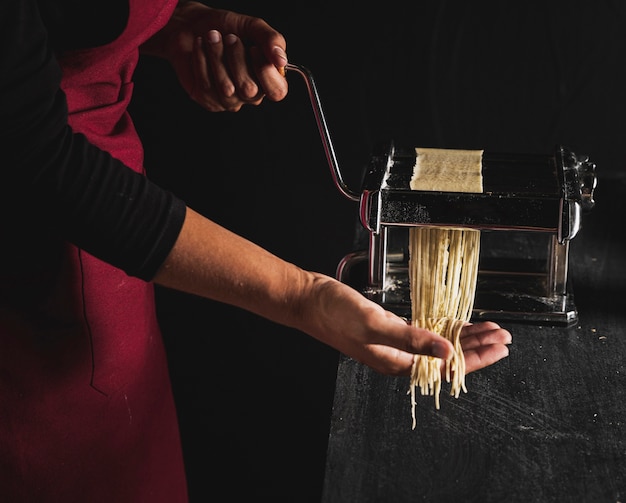 Persona del primo piano che produce pasta con la macchina