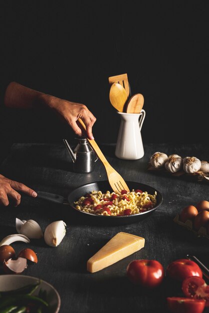 Close-up person mixing pasta in pan