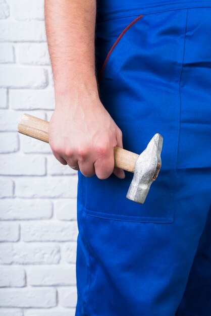 Close-up person in overalls with a hammer