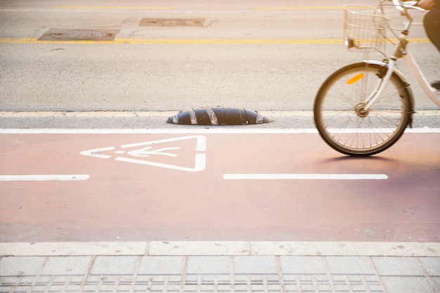 警告の三角形のサインが付いている道で自転車に乗る人のクローズアップ
