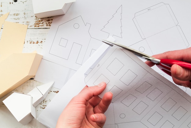 Close-up of a person's hand cutting the white paper with scissor