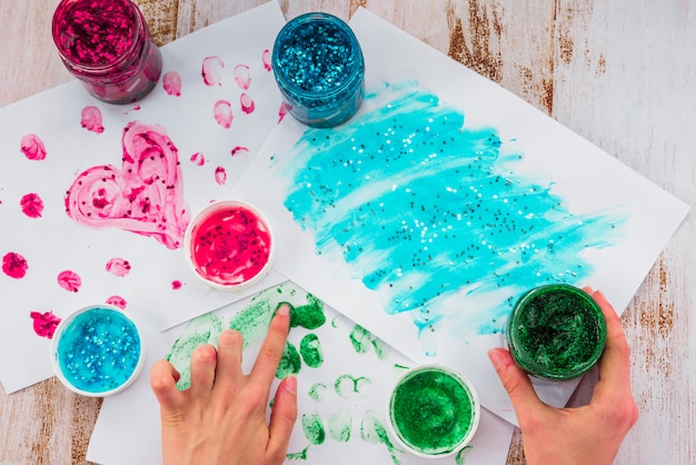 Close-up of a person's hand doing finger painting with using glitter color