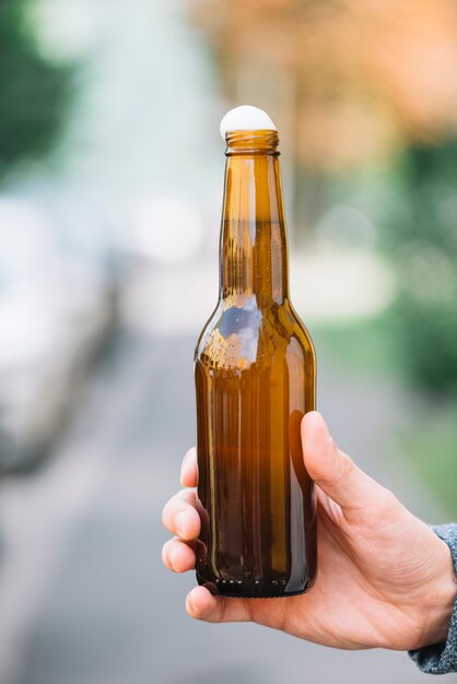 Close-up of a person's hand holding beer bottle
