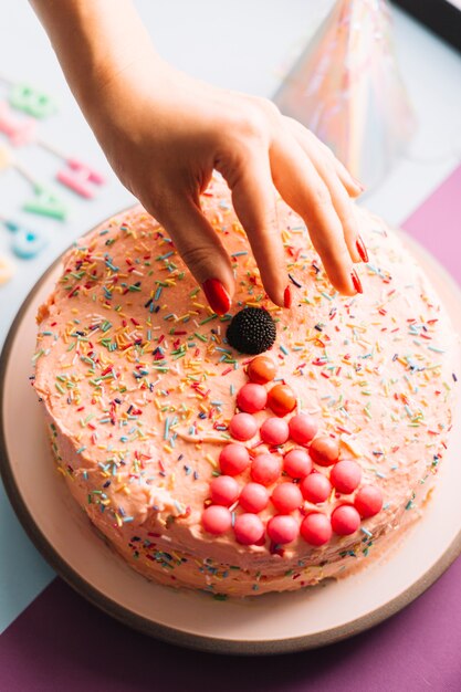 装飾されたケーキにチョコレートボールを保持している人の手のクローズアップ