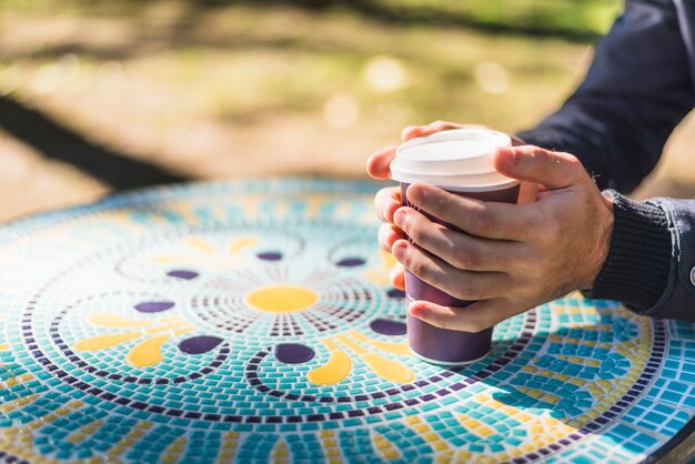 Close-up of a person's hand holding disposable coffee cup