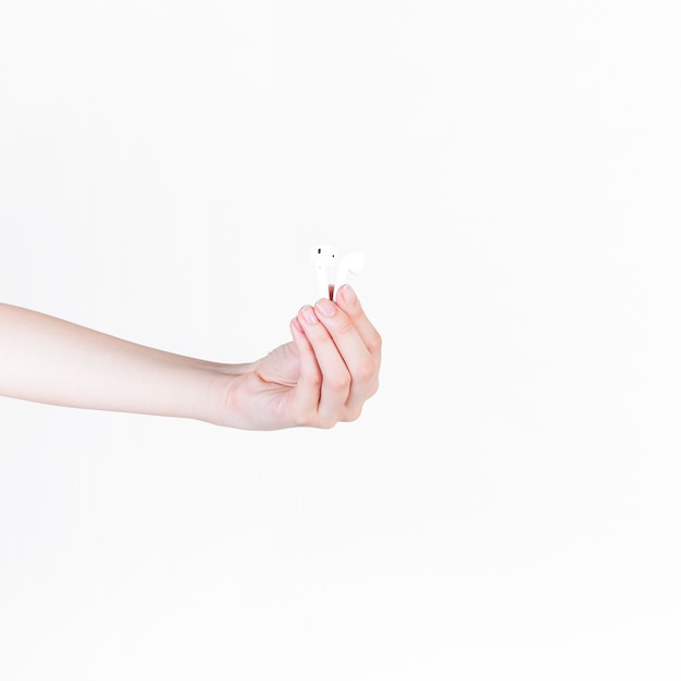 Close-up of a person's hand holding earphone on white background