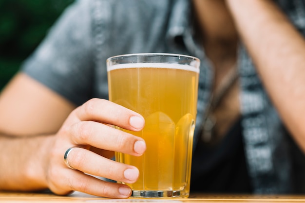 Close-up of a person's hand holding glass of beer