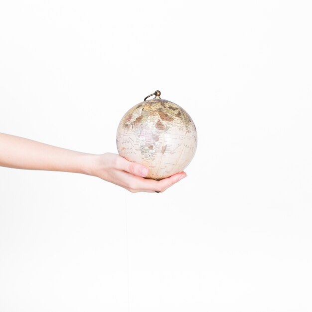 Close-up of a person's hand holding globe pendulum on white background