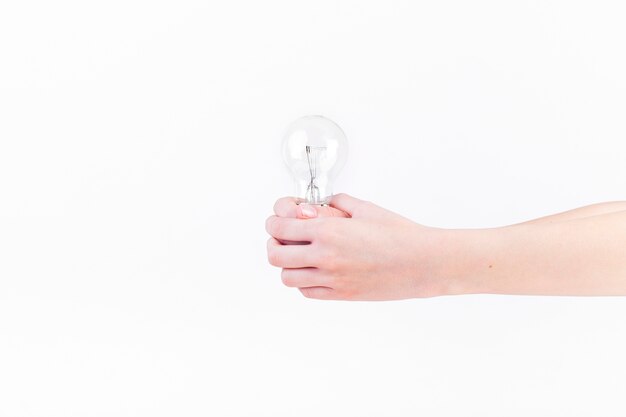 Close-up of a person's hand holding light bulb on white backdrop