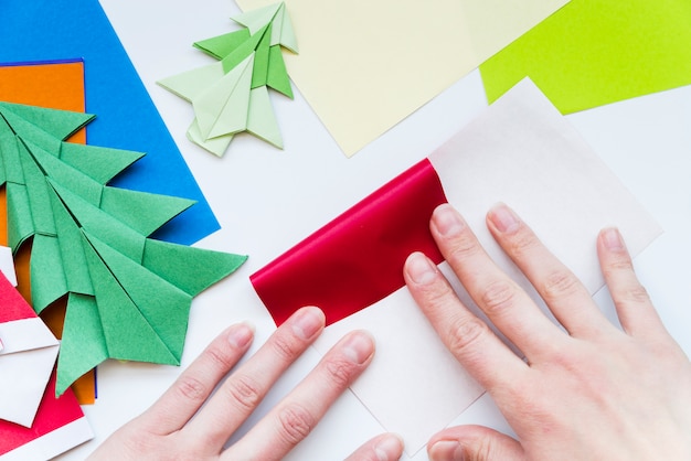 Close-up of a person's hand making the colorful paper isolated on white backdrop