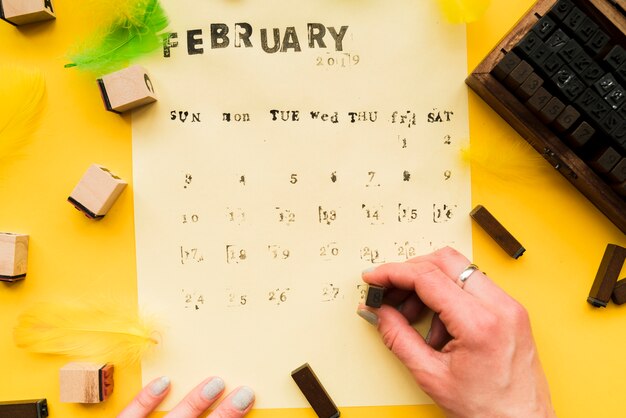 Close-up of a person's hand making the handmade february calendar with typographic blocks