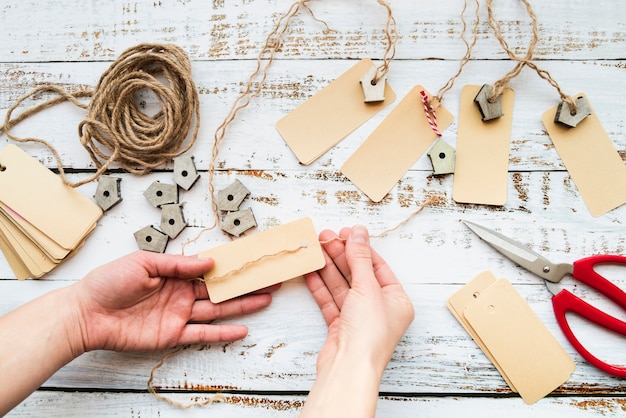 Free photo close-up of a person's hand making the tag and birdhouse garland on wooden table