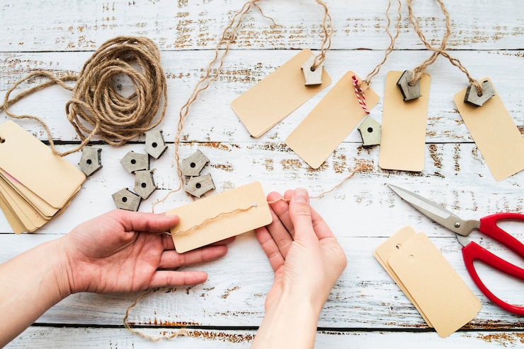 Free Photo close-up of a person's hand making the tag and birdhouse garland on wooden table