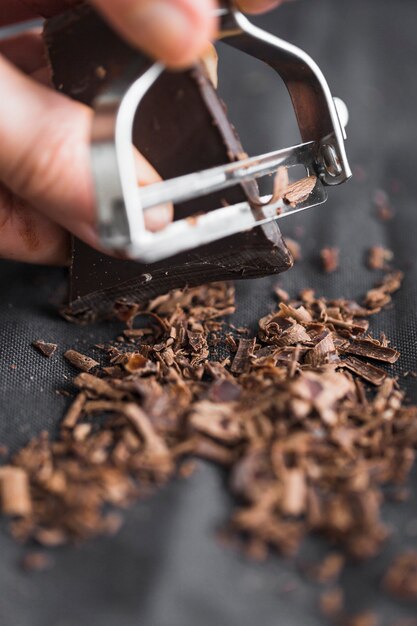 Close-up of person's hand shaving chocolate bar with peeler