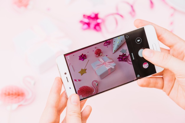 Close-up of a person's hand taking photo of birthday gifts and decoration on smart phone