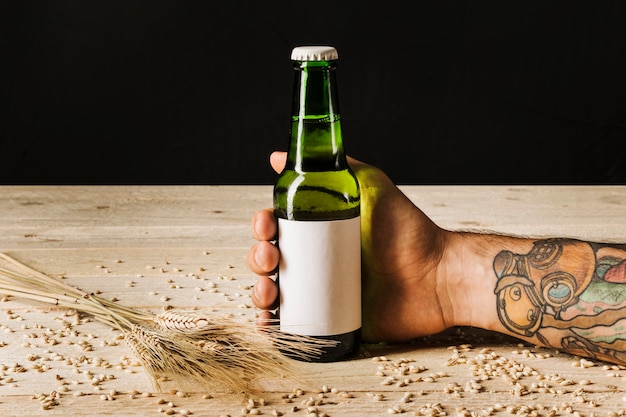 Free photo close-up of a person's hand with ears of wheat on wooden plank