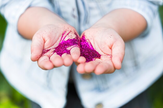 Close-up of a person's hand with pink glitters