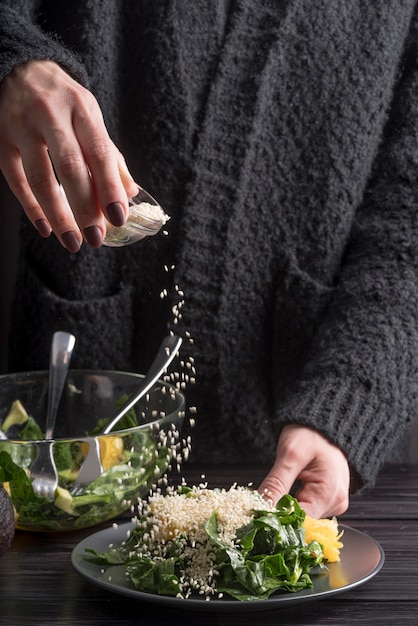 Free photo close-up person seasoning salad with salt