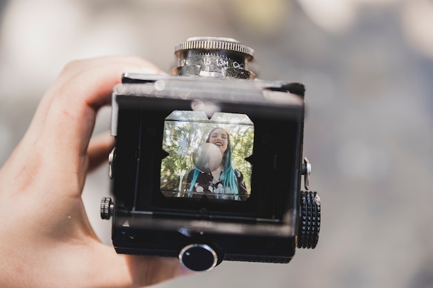 Close-up of a person showing smiling photo of a woman on vintage camera