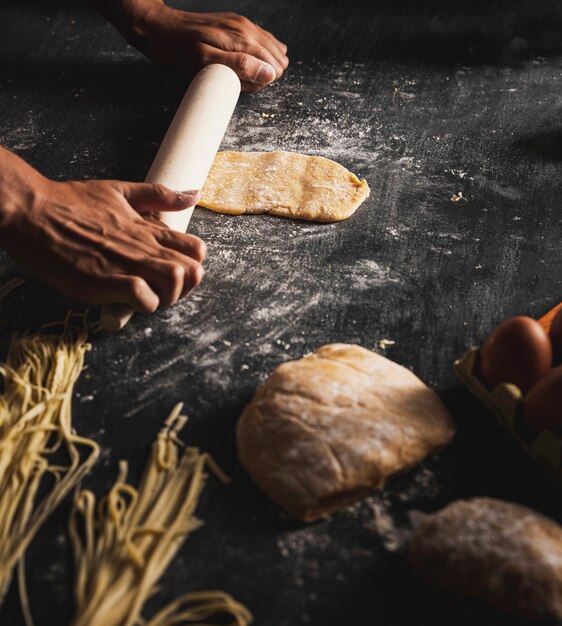 Close-up person spreading dough on black table